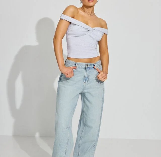 model wearing light wash garage barrel jeans with white top
