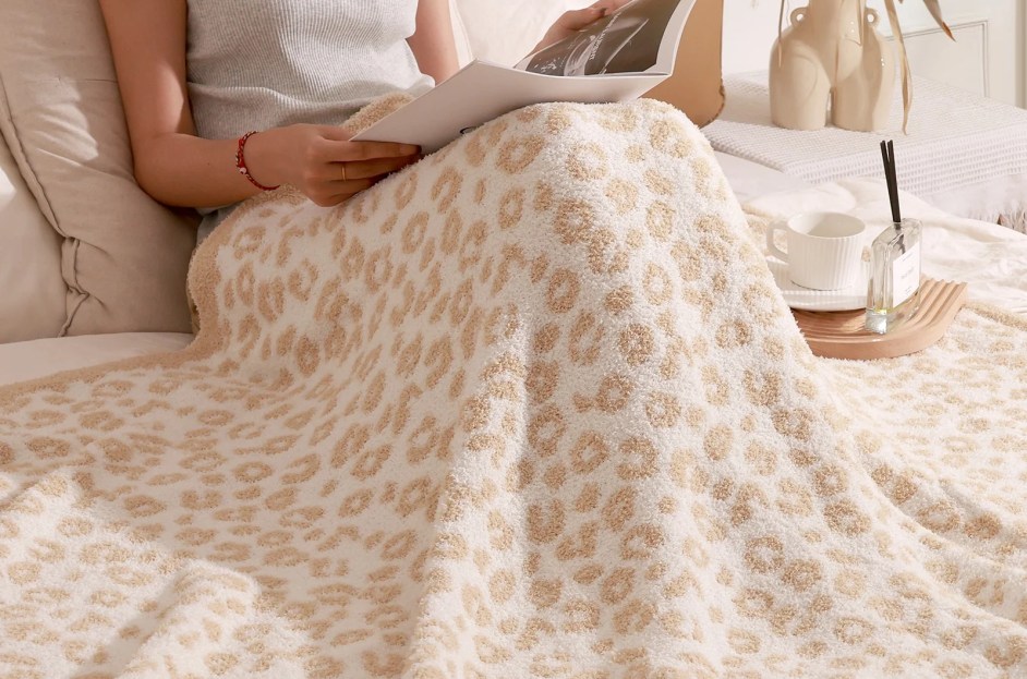 model laying in bed with camel and white cheetah blanket
