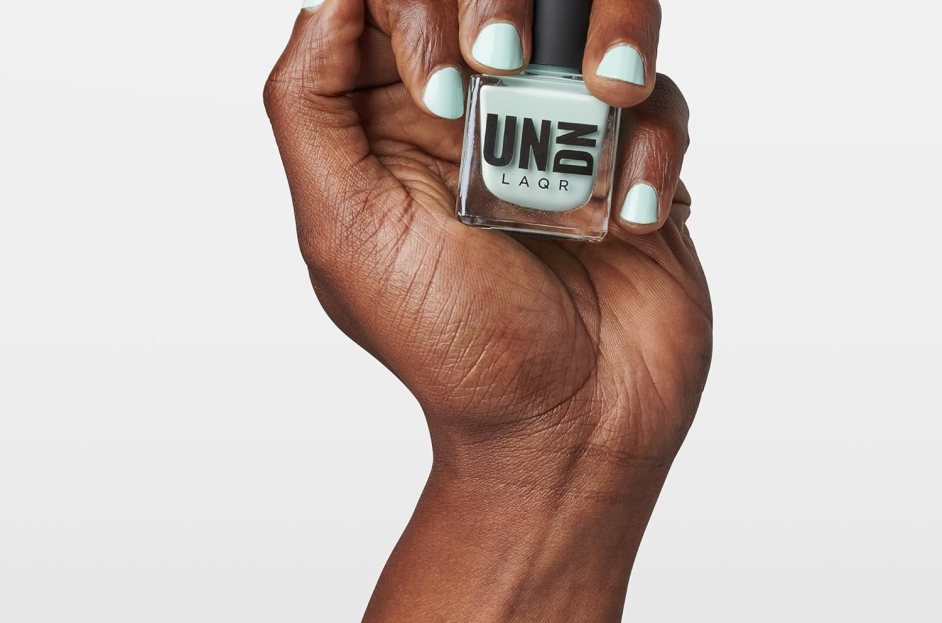 model wearing teal nail polish and holding bottle