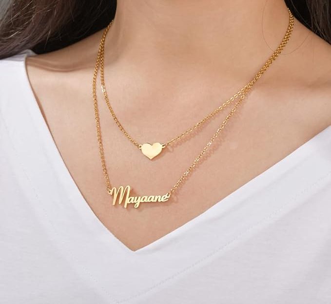 heart charm necklace above gold nameplate necklace
